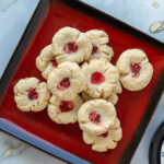 Stack of crumbly Chinese almond cookies with bright red dots on a red square plate.