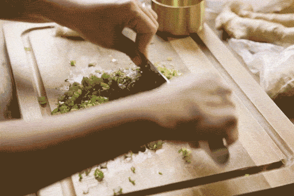 Green onions are finely chopped on a cutting board for ginger scallion sauce.