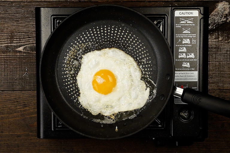 Sunny-side up egg cooking in butter in a skillet for loco moco recipe, whites fully set with a bright runny yolk