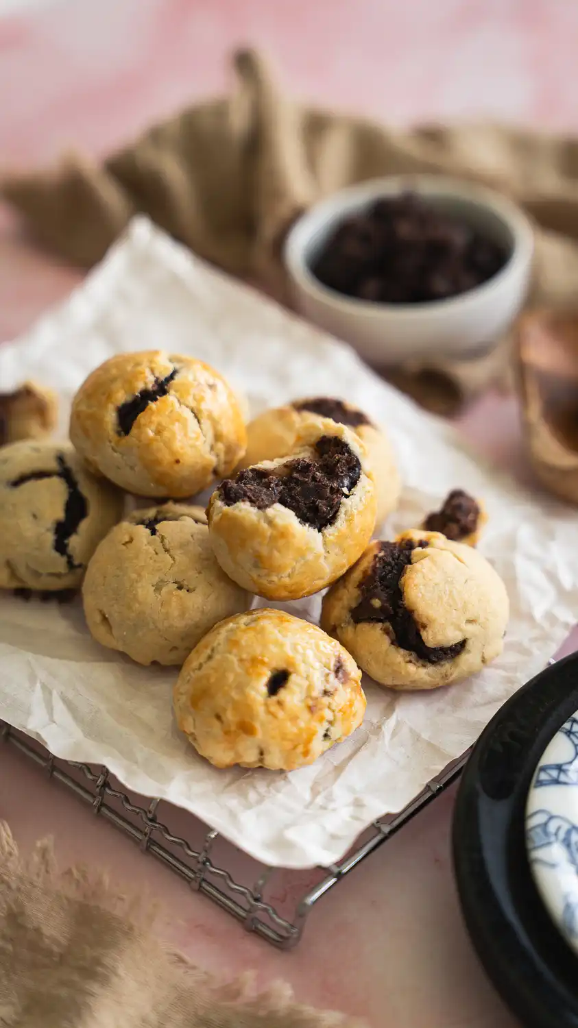 Golden baked anko buns with flaky crust and sweet red bean filling, stacked on parchment paper over a cooling rack