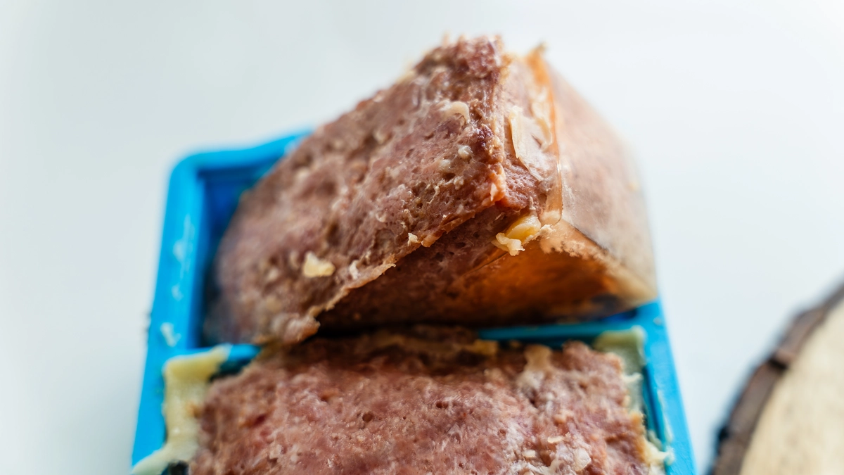 Close-up of homemade SPAM in a blue silicone mold showing the natural clear gelatin layer on the bottom of the cooked loaf