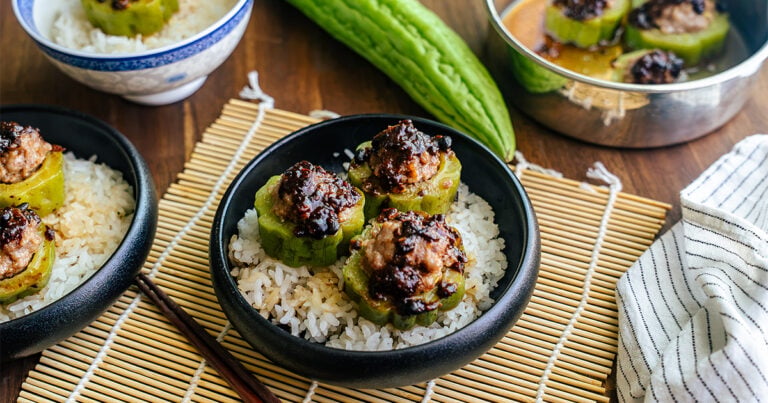 Bowl of steamed stuffed bitter melon with pork hash and black bean sauce served over rice