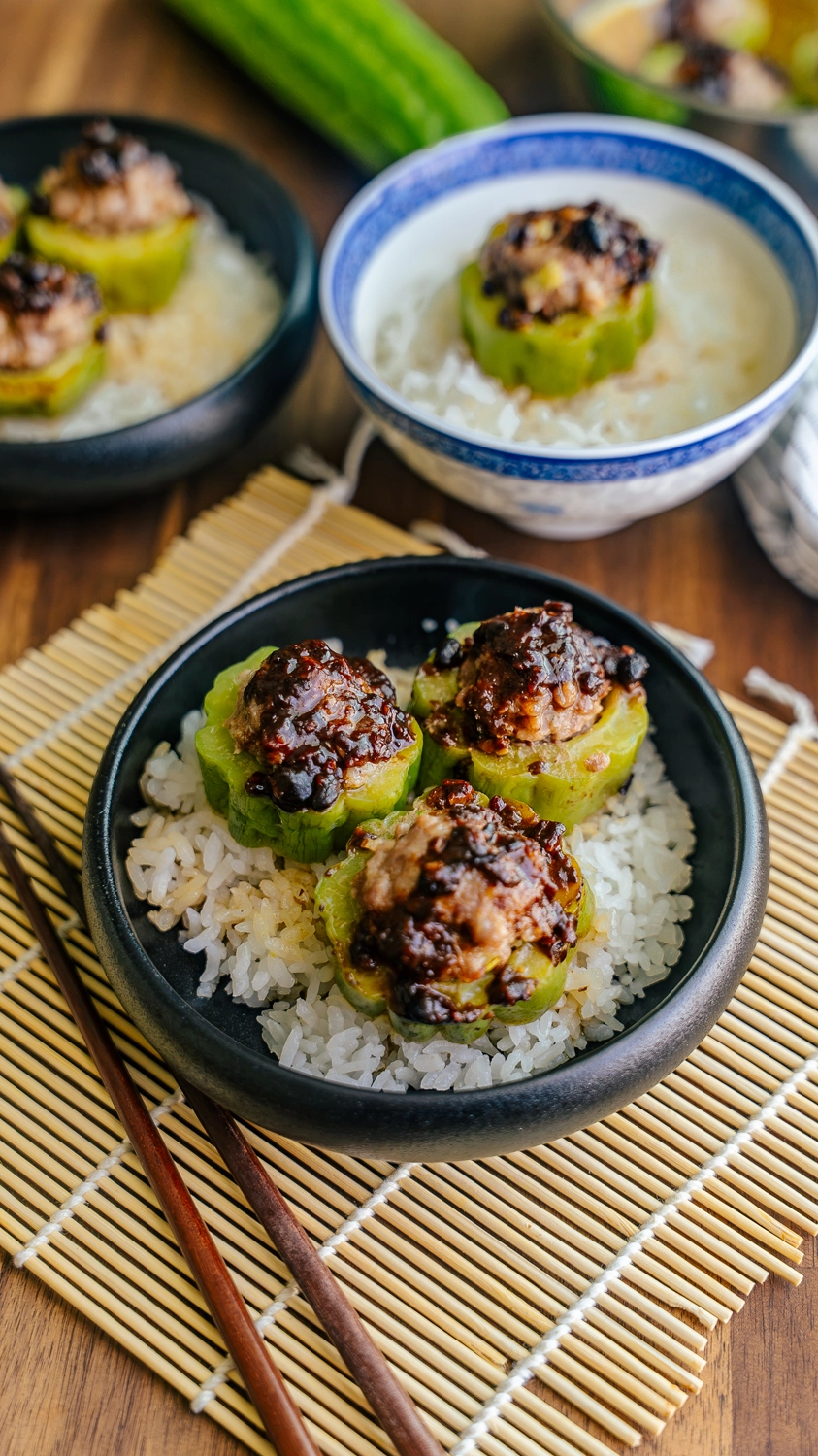 Bowl of steamed stuffed bitter melon with pork hash and black bean sauce served over rice