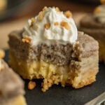 Close-up square crop of a kulolo crunch bar with a bite removed, revealing the golden crust and custardy poi layer beneath a peak of whipped cream and toasted macadamia crumble.